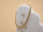 18K gold-plated waterproof tarnish-free chain bracelet handmade and woman owned by CHRMD, draped over a marble display.