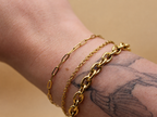 18K gold-plated waterproof tarnish-free chain bracelets handmade and woman owned by CHRMD, draped over a marble display.