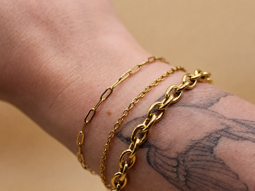 18K gold-plated waterproof tarnish-free chain bracelets handmade and woman owned by CHRMD, draped over a marble display.